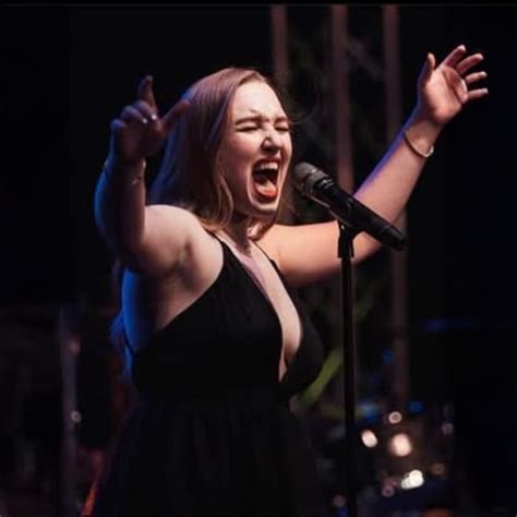 Coco Lane Rigbye singing passionately into a microphone on stage